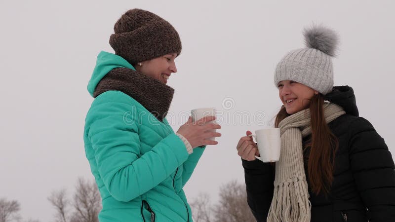Las muchachas congeladas en bebidas calientes que hablan y de consumiciones frías de los vidrios ríen la sonrisa imagen de archivo