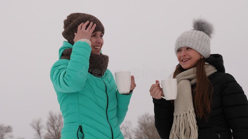 Las muchachas congeladas en bebidas calientes que hablan y de consumiciones frías de los vidrios ríen la sonrisa imagen de archivo
