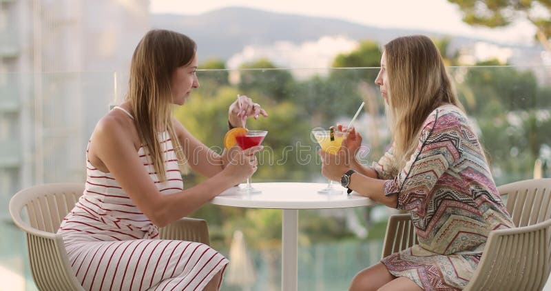 Las mujeres adultas alegres están bebiendo un cóctel en la terraza del hotel