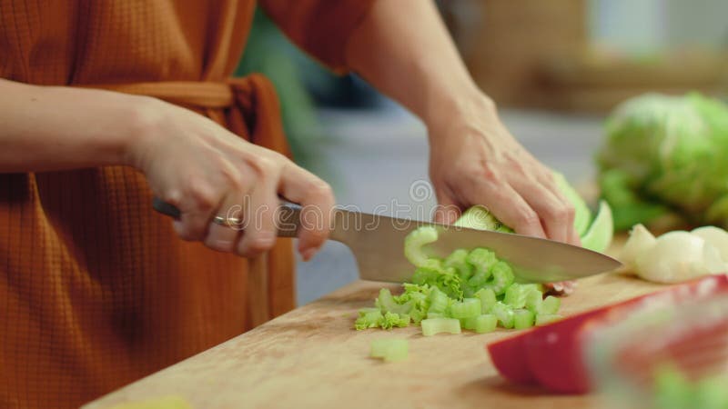 Las mujeres cortan el apio en la tabla de corte El ama de casa cocina verduras frescas