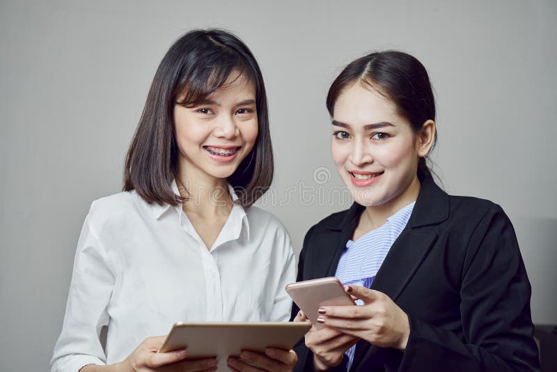Las mujeres de negocios sonrientes están celebrando la tableta y usar usos en línea imagenes de archivo Las mujeres de negocios sonrientes están celebrando la tableta y usar usos en línea imagenes de archivo