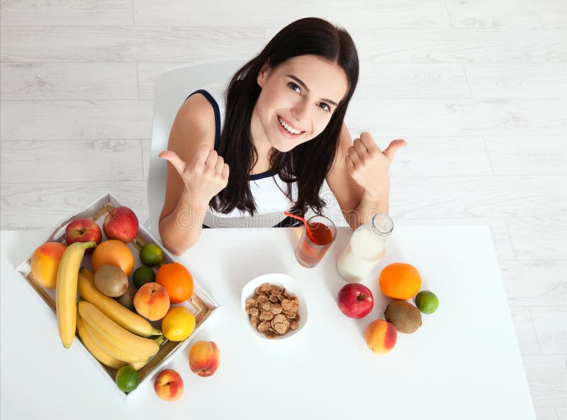 Las mujeres hermosas existen con la piel pura en su cara que se sienta en una tabla y comen a la mujer asiática del desayuno que foto de archivo libre de regalías Las mujeres hermosas existen con la piel pura en su cara que se sienta en una tabla y comen a la mujer asiática del desayuno que foto de archivo libre de regalías