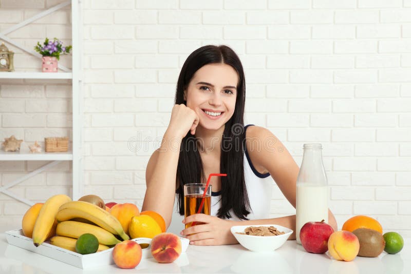 Las mujeres hermosas existen con la piel pura en su cara que se sienta en una tabla y comen a la mujer asiática del desayuno que imagen de archivo Las mujeres hermosas existen con la piel pura en su cara que se sienta en una tabla y comen a la mujer asiática del desayuno que imagen de archivo