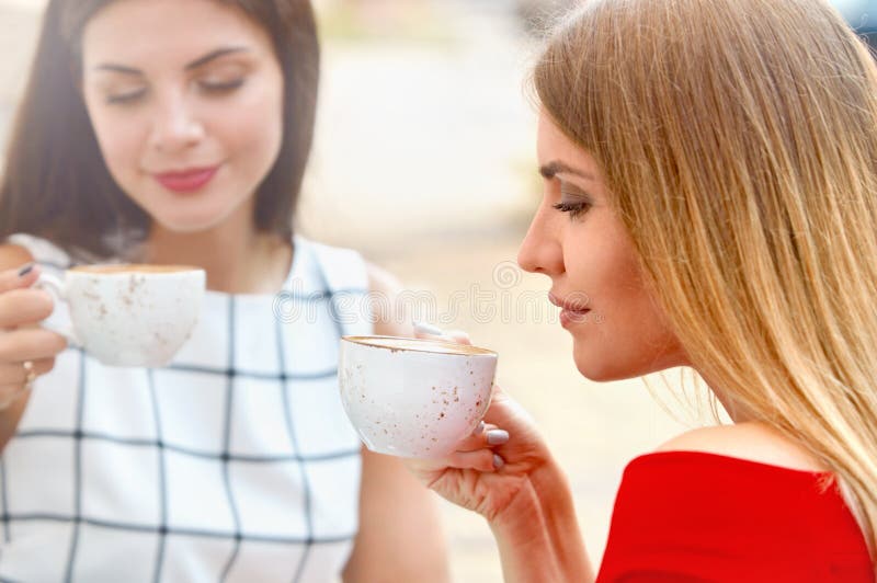 Las mujeres jovenes atractivas beben el café en ciudad del verano foto de archivo libre de regalías Las mujeres jovenes atractivas beben el café en ciudad del verano foto de archivo libre de regalías