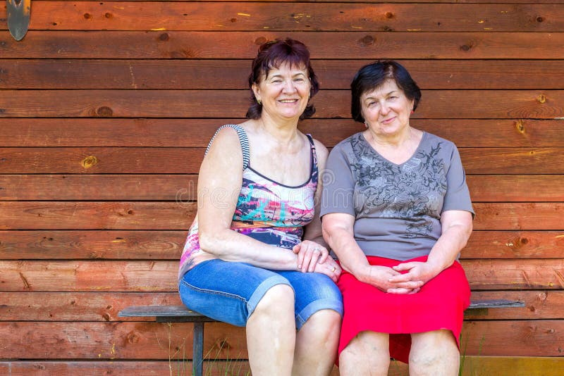 Las mujeres maduras hermosas están descansando sobre un banco fotografía de archivo Las mujeres maduras hermosas están descansando sobre un banco fotografía de archivo