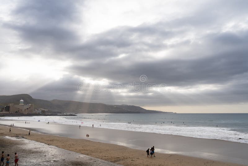 Sun rays piercing clouds over Las Canteras beach in Gran Canaria royalty free stock image