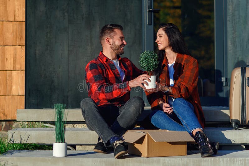 Las parejas jóvenes que se sientan en las escaleras deportivos que desempaca las cajas después de pasar a la nueva casa. imagenes de archivo