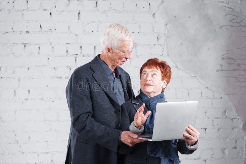 Las personas mayores sostienen un ordenador portátil y comunican a través de Internet Pares sonrientes felices de la abuela del a imágenes de archivo libres de regalías Las personas mayores sostienen un ordenador portátil y comunican a través de Internet Pares sonrientes felices de la abuela del a imágenes de archivo libres de regalías