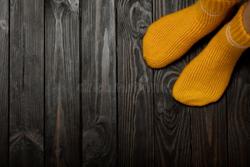 Las piernas amarillean calcetines de lana hechos punto en fondo oscuro de madera fotos de archivo libres de regalías Las piernas amarillean calcetines de lana hechos punto en fondo oscuro de madera fotos de archivo libres de regalías
