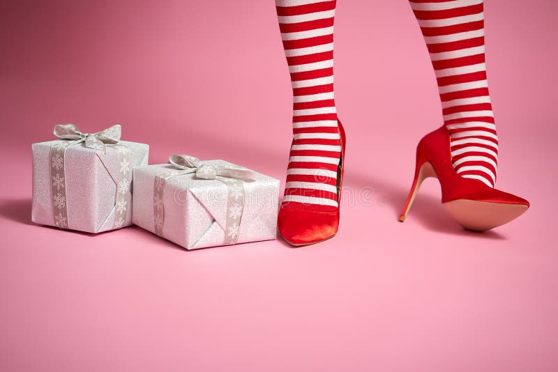 santa woman`s legs on a bright pink background and Christmas gifts. santa woman`s legs on a bright pink background and Christmas gifts