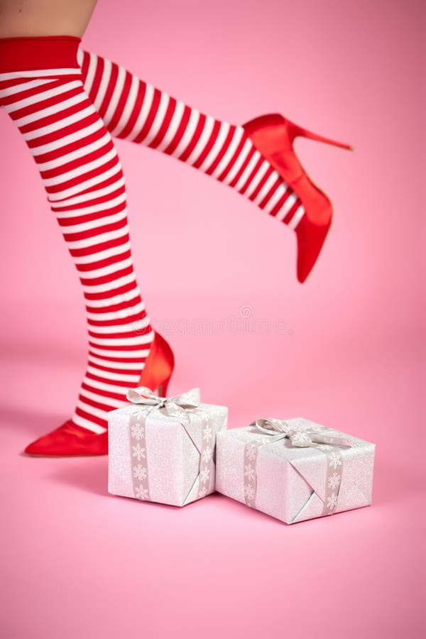 santa woman`s legs on a bright pink background and Christmas gifts. santa woman`s legs on a bright pink background and Christmas gifts