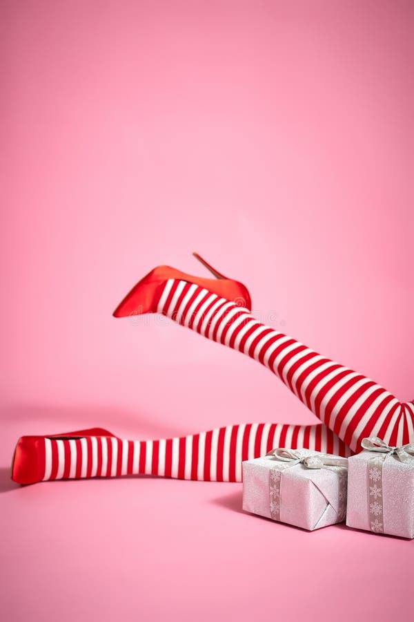 santa woman`s legs on a bright pink background and Christmas gifts. santa woman`s legs on a bright pink background and Christmas gifts