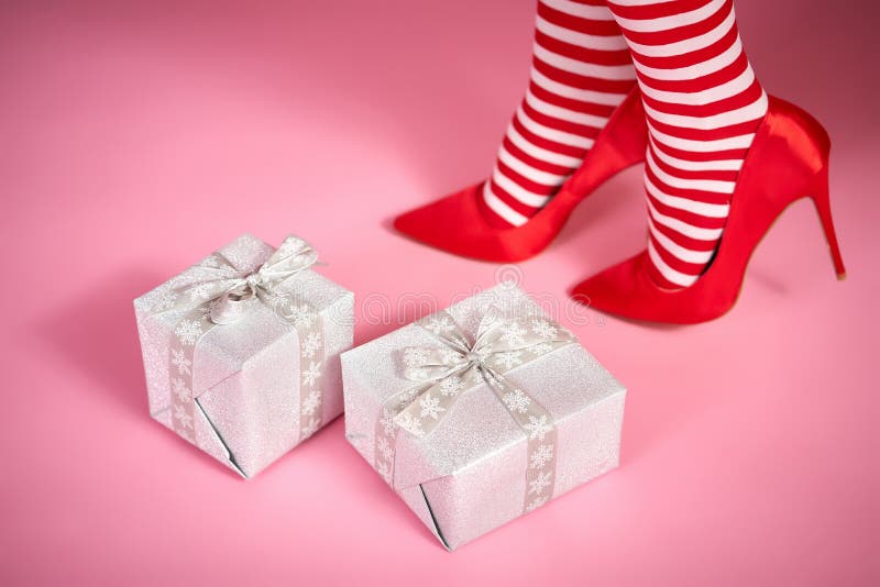 santa woman`s legs on a bright pink background and Christmas gifts. santa woman`s legs on a bright pink background and Christmas gifts