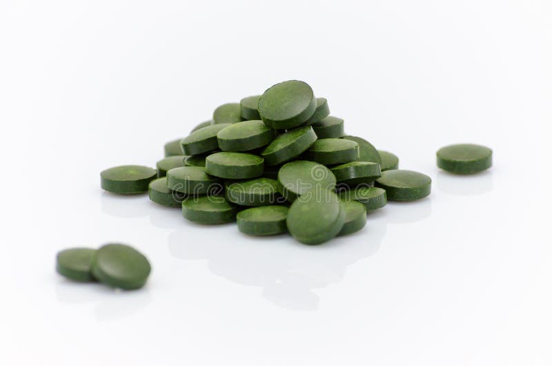 Las píldoras verdes de la alga marina de la Chlorella del spirulina se cierran para arriba en blanco fotos de archivo libres de regalías Las píldoras verdes de la alga marina de la Chlorella del spirulina se cierran para arriba en blanco fotos de archivo libres de regalías