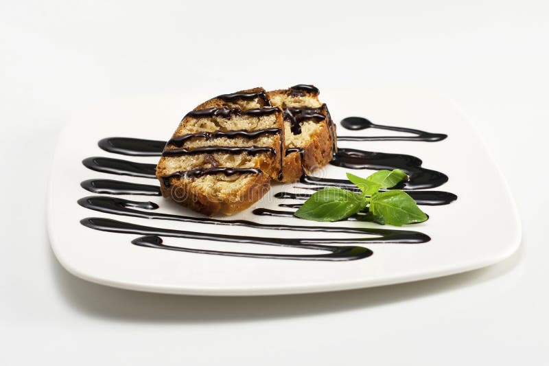 Las rebanadas del queque de frutas con la salsa de chocolate y la menta verde hojean. imagen de archivo libre de regalías Las rebanadas del queque de frutas con la salsa de chocolate y la menta verde hojean. imagen de archivo libre de regalías