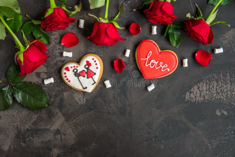 Las rosas rojas y la galleta formaron el corazón con el amor del texto, backgroun oscuro imagen de archivo Las rosas rojas y la galleta formaron el corazón con el amor del texto, backgroun oscuro imagen de archivo
