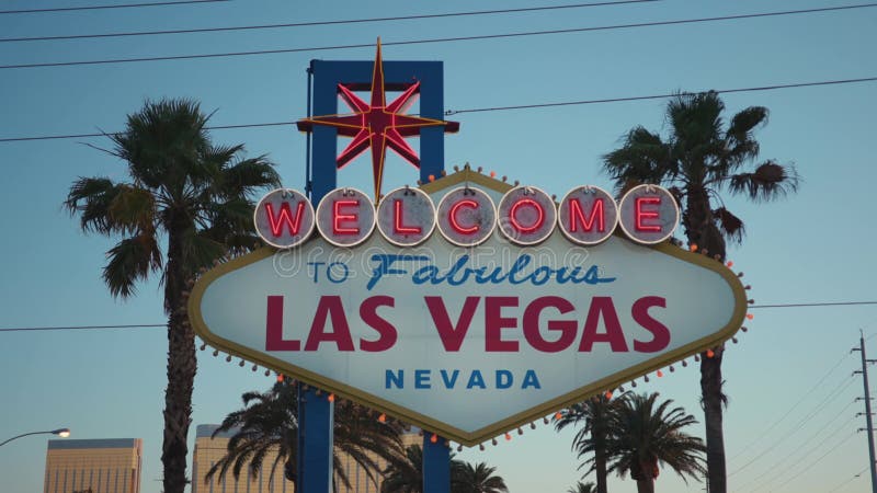 Las Vegas sign against palm trees at sunrise