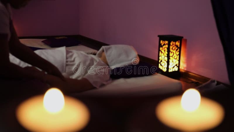 Las velas arden cerca de la mujer que hace masaje a mano almacen de video