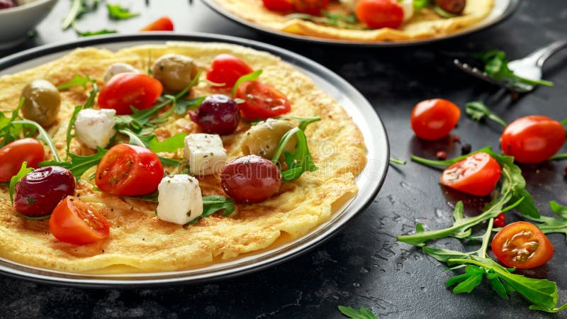Las verduras Eggs la tortilla con los tomates, cohete salvaje, queso griego, aceitunas en una placa Comida sana del desayuno de l fotografía de archivo Las verduras Eggs la tortilla con los tomates, cohete salvaje, queso griego, aceitunas en una placa Comida sana del desayuno de l fotografía de archivo