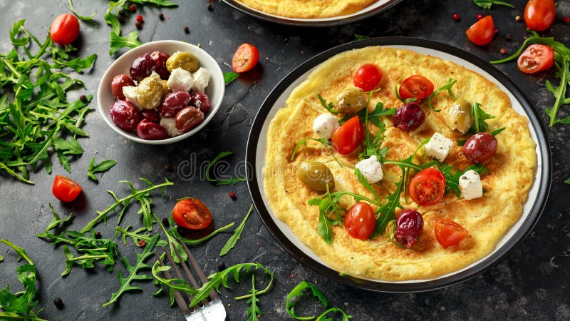 Las verduras Eggs la tortilla con los tomates, cohete salvaje, queso griego, aceitunas en una placa Comida sana del desayuno de l imagen de archivo Las verduras Eggs la tortilla con los tomates, cohete salvaje, queso griego, aceitunas en una placa Comida sana del desayuno de l imagen de archivo