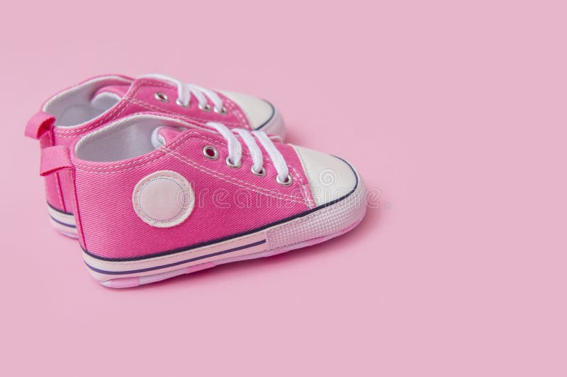 Las zapatillas de deporte rosadas lindas del bebé se cierran para arriba en fondo rosado fotos de archivo libres de regalías Las zapatillas de deporte rosadas lindas del bebé se cierran para arriba en fondo rosado fotos de archivo libres de regalías