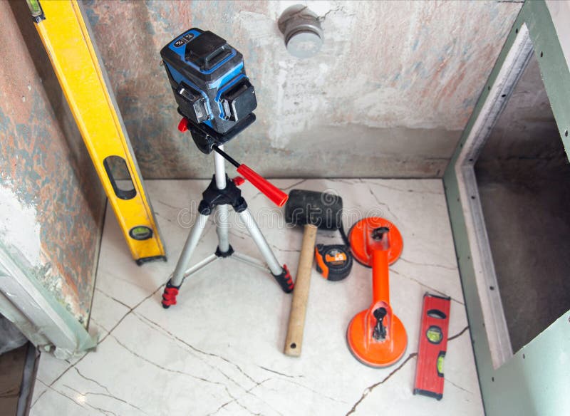 Laser building level, rubber mallet and suction cup for laying tiles on walls and floors. The concept of repairing and laying stock photography