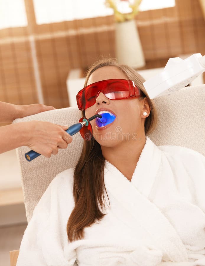 Young woman getting laser tooth whitening treatment at spa.