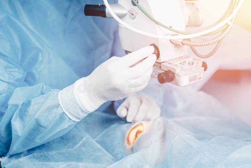 Lasik treatment. Laser vision correction. Doctor examines fundus in microscope, patient under sterile cover.