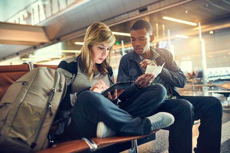 Last Checks If Everything is in Order. a Young Couple Using a Tablet in an Airport. Stock Photo