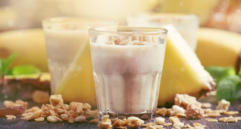 Lat smoothies z bananem, ananasem i granola, ciemny kuchennego stołu tło, selekcyjna ostrość fotografia stock Lat smoothies z bananem, ananasem i granola, ciemny kuchennego stołu tło, selekcyjna ostrość fotografia stock