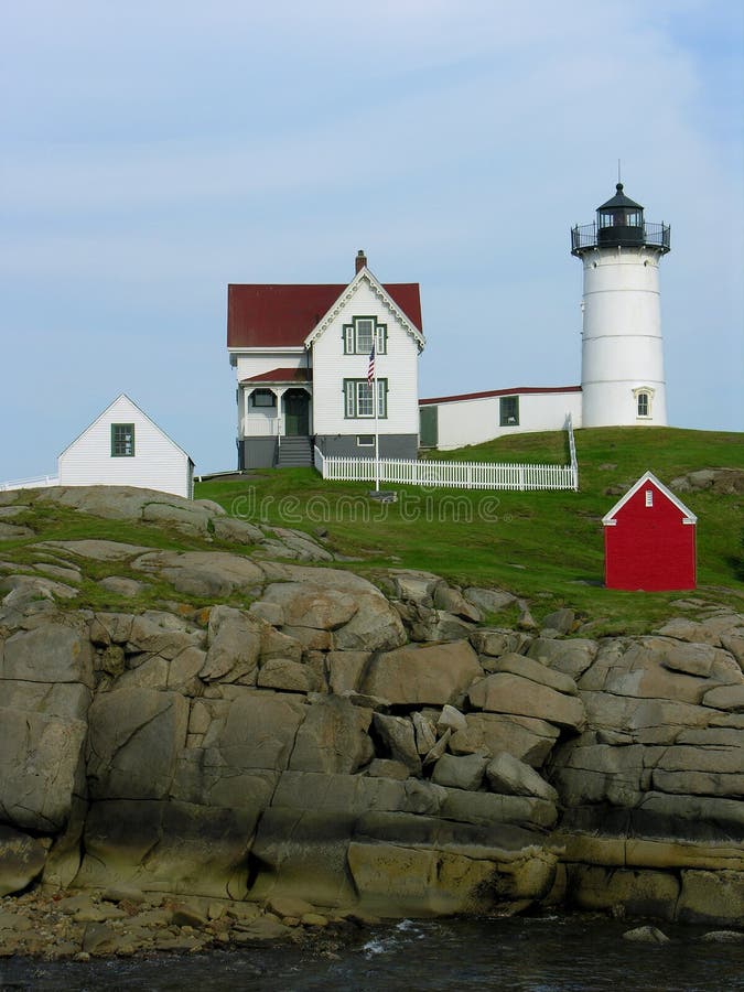 A white lighthouse stands on the rugged shoreline of Maine. A white lighthouse stands on the rugged shoreline of Maine