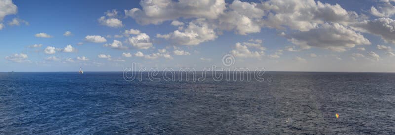 Late afternoon HDR panorama photo of sea spanning all the way to the horizon and blue cloudy sky