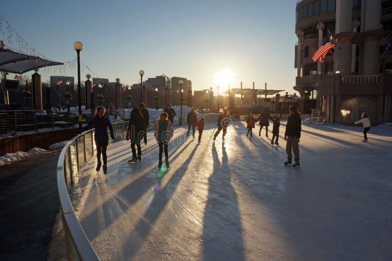 Photo of skaters at an ice rink at the georgetown waterfront in washington dc on 2/27/15. The setting sun adds some warmth on a cold day. This ice skating rink is very popular in the winter. Photo of skaters at an ice rink at the georgetown waterfront in washington dc on 2/27/15. The setting sun adds some warmth on a cold day. This ice skating rink is very popular in the winter.