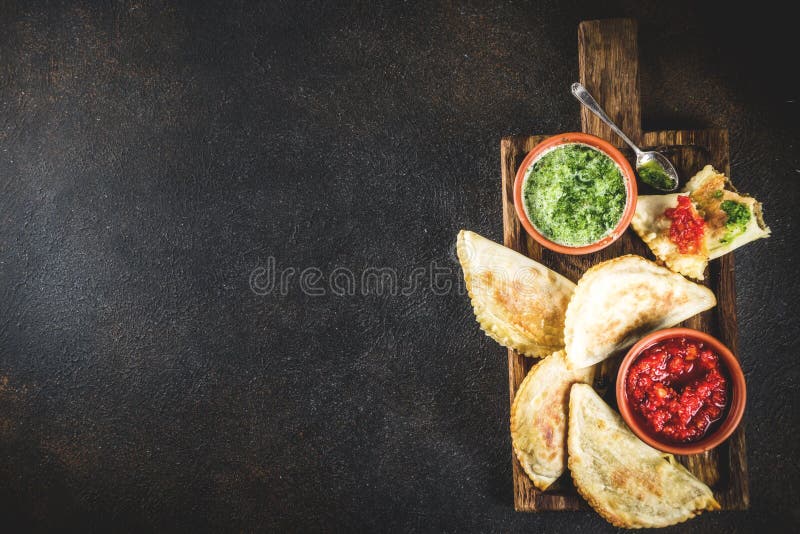 Latin American food, empanadas. Latin American, mexican, chilean food. Traditional baked pastry empanadas with beef meat, two spicy sauces, dark rusty background royalty free stock photo Latin American food, empanadas. Latin American, mexican, chilean food. Traditional baked pastry empanadas with beef meat, two spicy sauces, dark rusty background royalty free stock photo