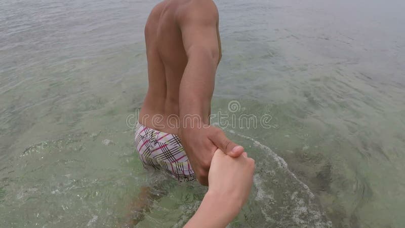 Latin man walk in sea water holding hand talking action camera pov of young couple on seaside