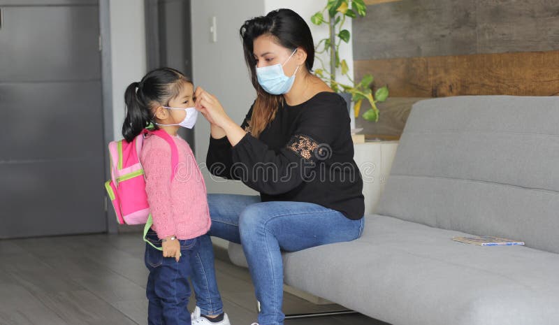 Latin mom and 3 year old girl with protective face masks and backpack for back to school, new normal covid-19