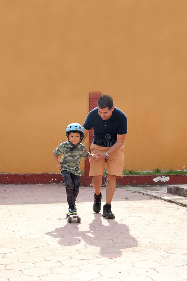 Latin Single Dad Teaches His Son To Ride a Skateboard with a image