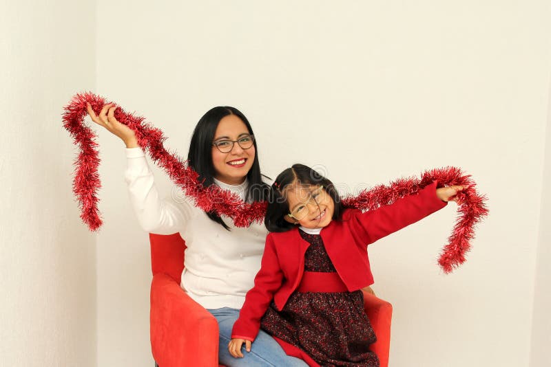 Latina Mom And Daughter With Glasses Hat And Christmas Garland Show Their Enthusiasm And