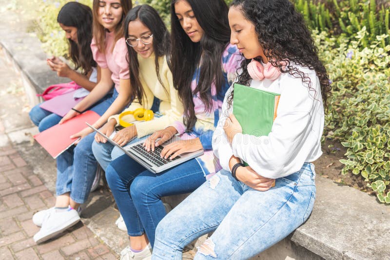 Latina teen girls working on laptop outdoors stock images