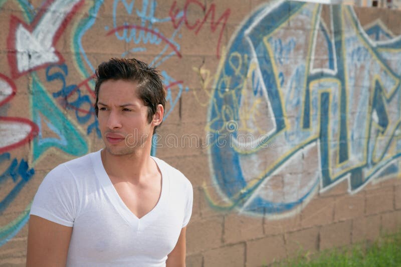 Mladá latino muž stojí pred graffiti.