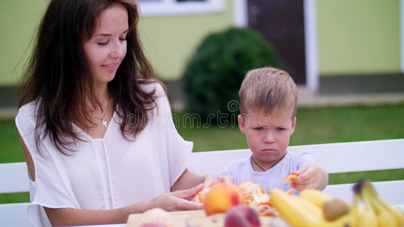 Lato, w ogródzie Mama i czteroletni syn czyściliśmy od łup pomarańcz chcą robić świeżemu sokowi