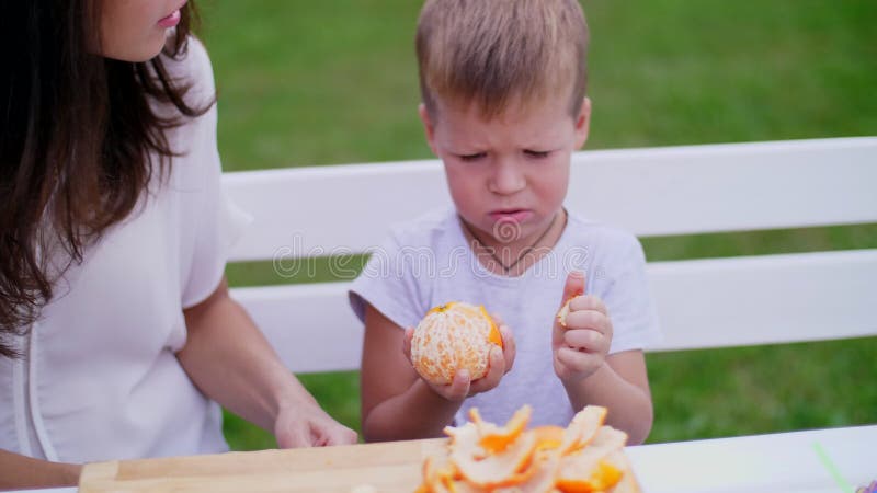 Lato, w ogródzie Mama i czteroletni syn czyściliśmy od łup pomarańcz chcą robić świeżemu sokowi