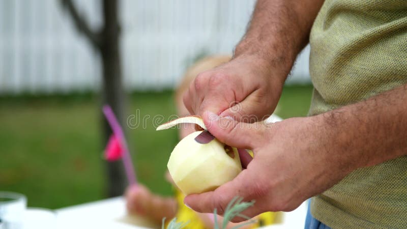 Lato, w ogródzie, zwolnione tempo, zakończenie, mężczyzna ` s ręki, struga jabłka z nożem, ciie łupę