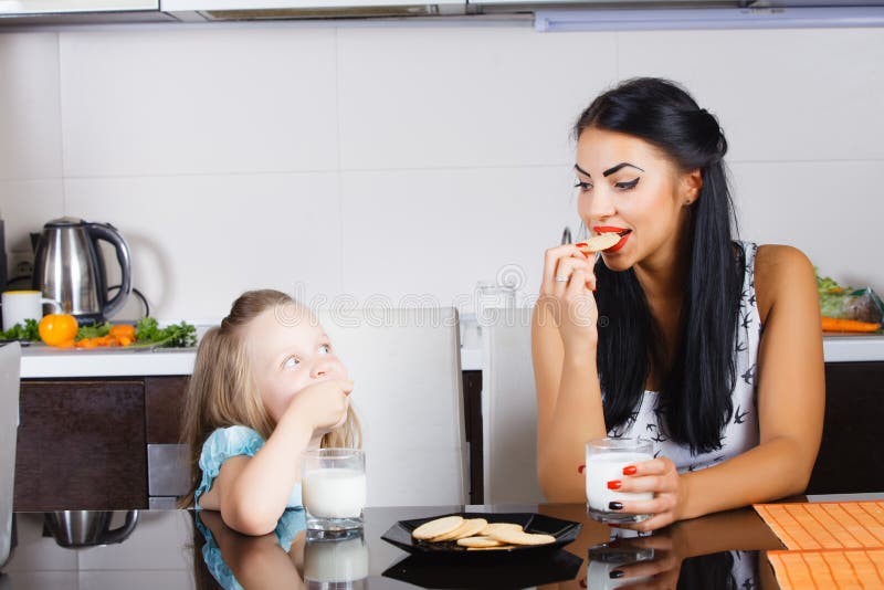 Latte alimentare e biscotti della bella bambina fotografie stock libere da diritti Latte alimentare e biscotti della bella bambina fotografie stock libere da diritti