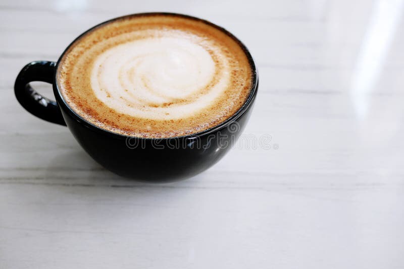 Latte caldo del cappuccino del caffè in tazza nera con la coclea mescolata MI fotografie stock