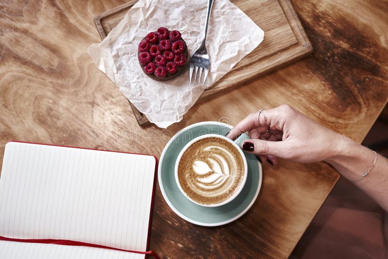 Latte della tazza di caffè sulla tavola di legno o fondo da sopra Pranzando in caffè Taccuino aperto, spazio per il modello di pr immagini stock libere da diritti