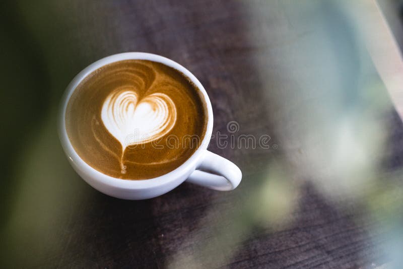 Latte en forma de corazón del café en la tabla de madera fotos de archivo Latte en forma de corazón del café en la tabla de madera fotos de archivo