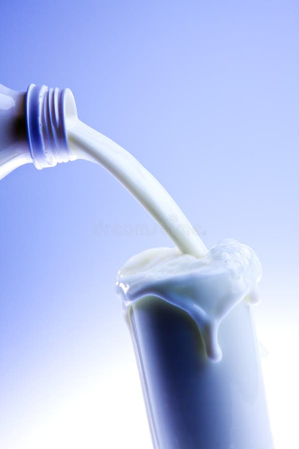 Latte fresco cremoso di versamento in un vetro trasparente fotografia stock Latte fresco cremoso di versamento in un vetro trasparente fotografia stock