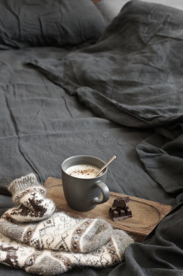 Latte кофе с шоколадом и шерстяные носки в отменятьой кровати стоковая фотография Latte кофе с шоколадом и шерстяные носки в отменятьой кровати стоковая фотография