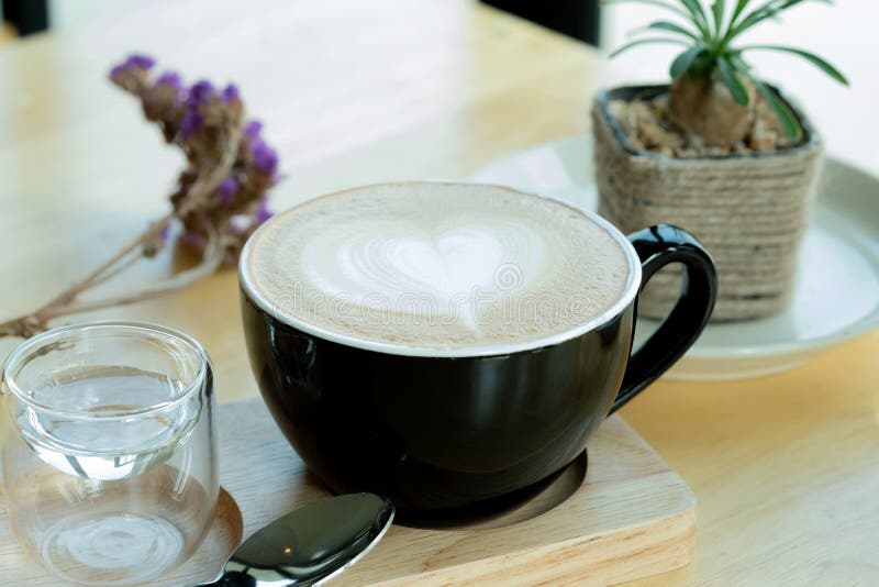 Lattekonstkaffe i morgontiden med solljus på trätabellbakgrund på coffee shop royaltyfria bilder Lattekonstkaffe i morgontiden med solljus på trätabellbakgrund på coffee shop royaltyfria bilder
